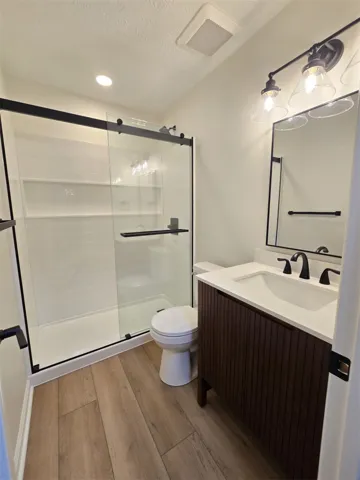 A well-appointed bathroom offers wood-look flooring and a contemporary vanity with a spacious shower.