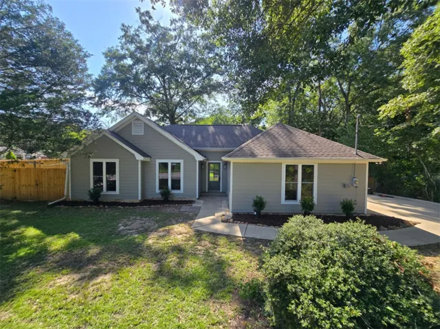A welcoming residence features a well-maintained lawn and mature trees, offering a serene outdoor setting.
