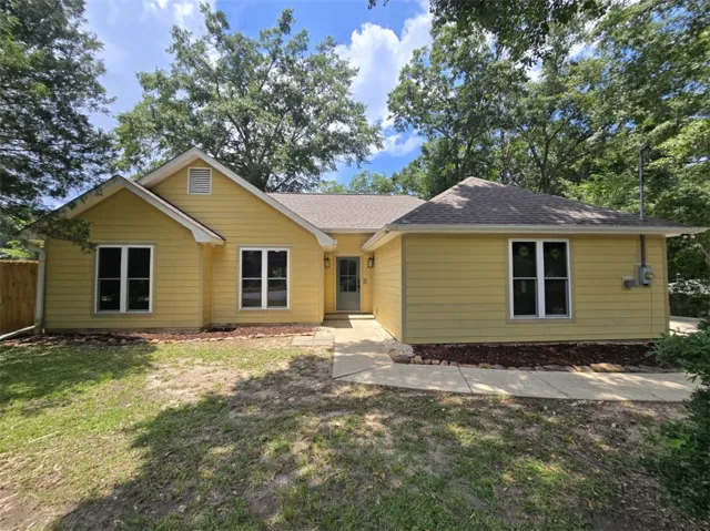 A cheerful facade welcomes you home, framed by mature trees and a neatly mulched landscape.