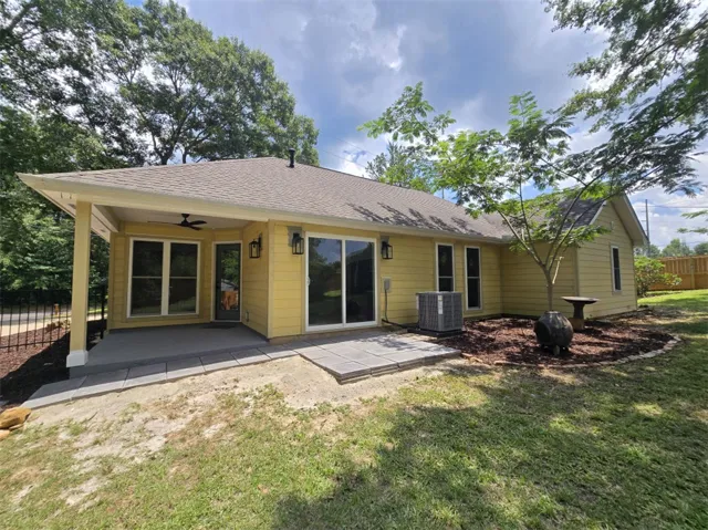 A cheerful yellow exterior invites outdoor enjoyment on the covered patio and open-air paver area.