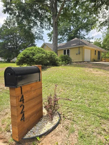 A charming yellow residence with a distinctive wooden mailbox and lush front yard.