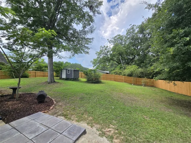 A fenced backyard offers a private retreat with mature trees and a convenient storage shed.