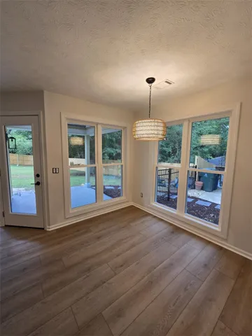 Hardwood-style flooring extends through this room, with multiple windows framing the private backyard.