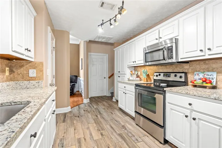 Granite counters and stainless steel appliances adorn this efficient culinary space, featuring durable wood-look tile flooring.