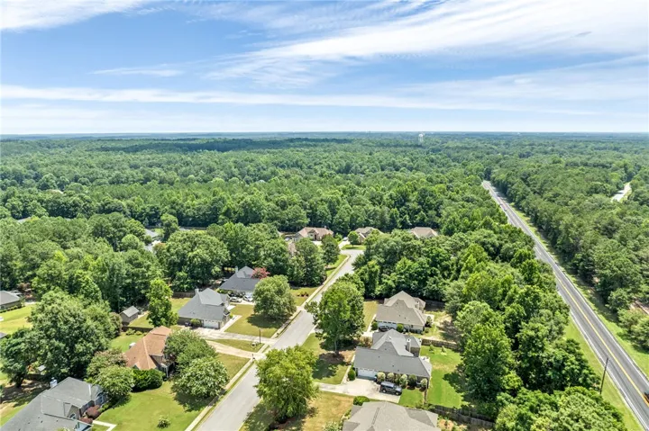 An aerial perspective reveals a serene residential area bordered by expansive, verdant woodlands.