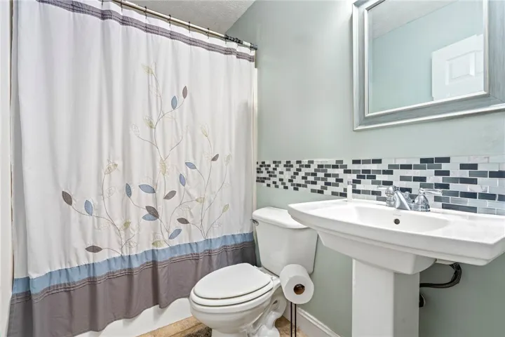 A compact bath space features a sleek pedestal sink and contemporary tiled accents.