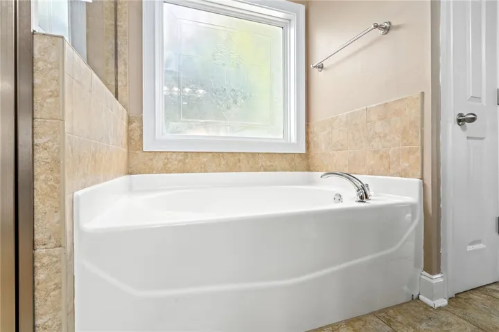 Indulge in a corner soaking tub, perfectly positioned beneath a decorative privacy window.