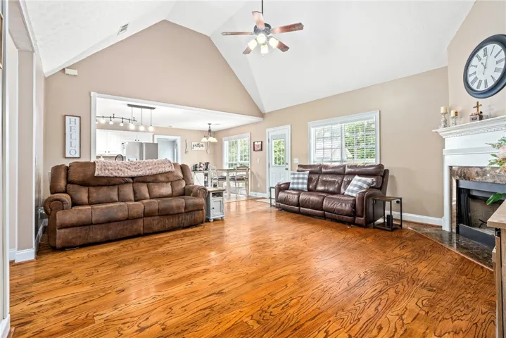 A vaulted ceiling living room features gleaming hardwood floors and a cozy fireplace.