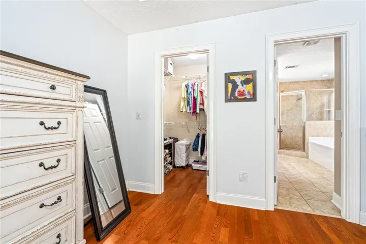 Rich hardwood floors lead to a spacious walk-in closet and adjoining bathroom.