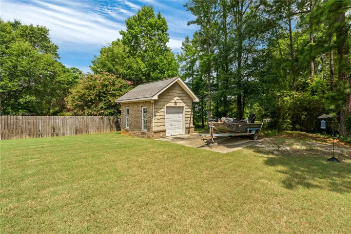 A quaint detached shed with a roll-up door sits amidst a spacious yard, offering versatile outdoor storage.
