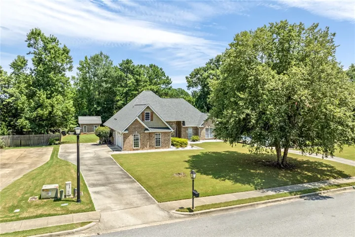 Mature trees frame this traditional brick home with an inviting driveway and spacious lawn.