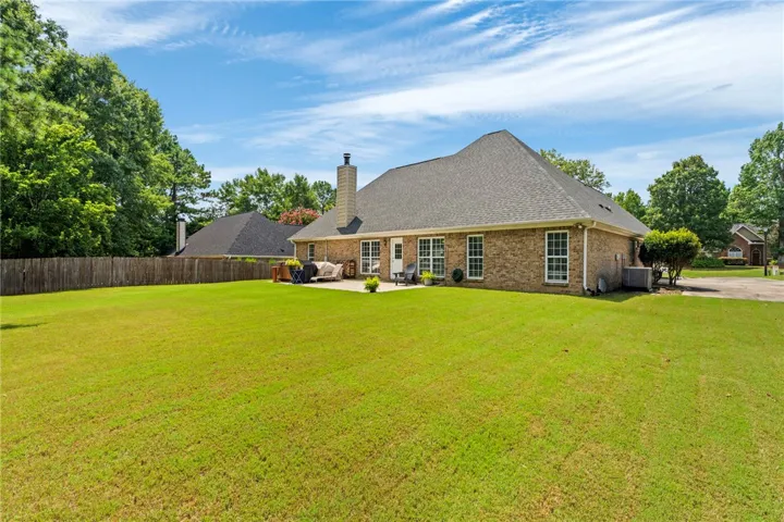 A spacious lawn unfolds behind a classic brick residence, offering ample outdoor living space.