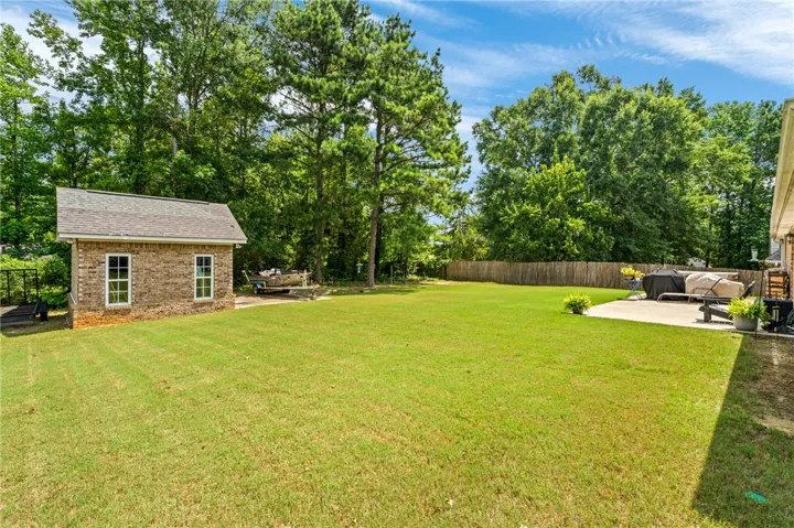 A spacious backyard features a separate brick outbuilding and a comfortable patio, perfect for outdoor relaxation.