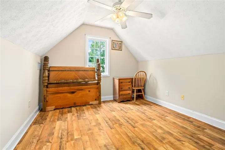 Bright, airy bedroom featuring a vaulted ceiling and rich hardwood flooring, offering a comfortable retreat.