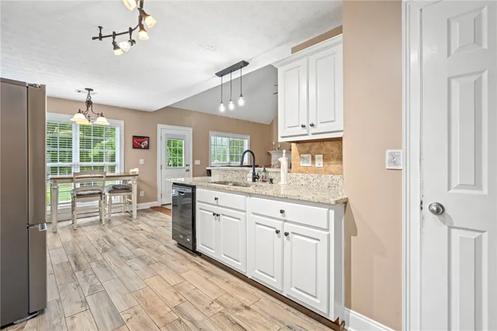 Granite counters and light wood flooring define this open-concept kitchen with crisp white cabinetry.