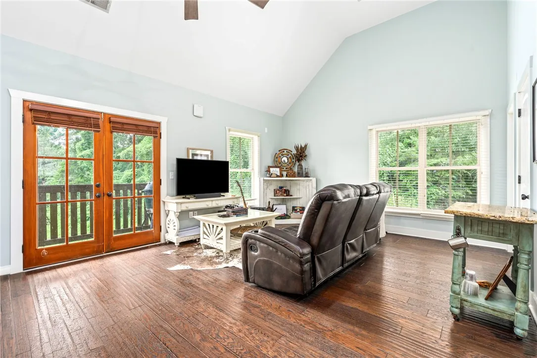 Natural light floods this inviting living space, highlighting rich hardwood floors and an expansive vaulted ceiling.