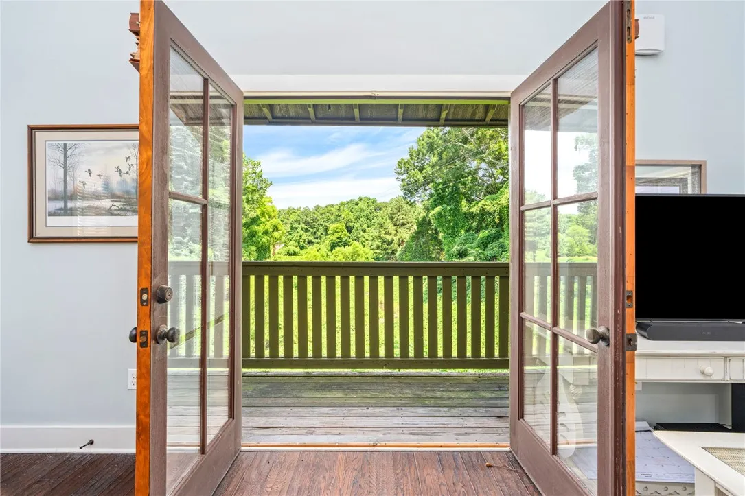 French doors open to a spacious deck, revealing a serene, wooded landscape.