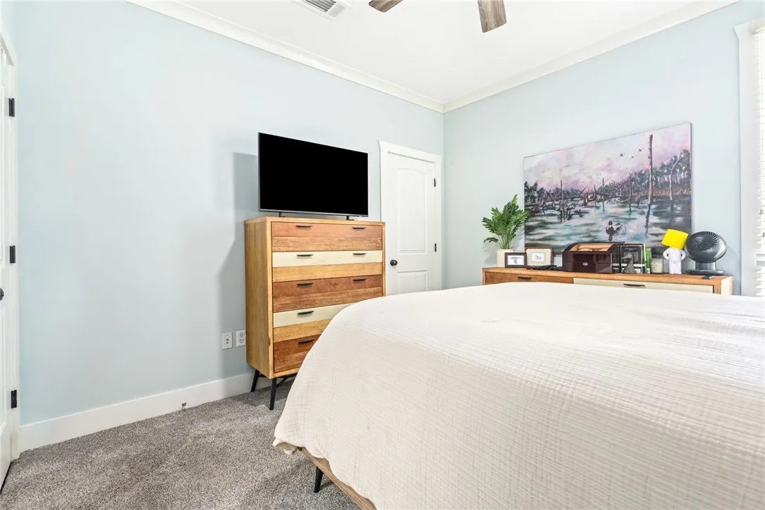 Relax in this tranquil bedroom, featuring a warm carpeted floor and crisp crown molding.