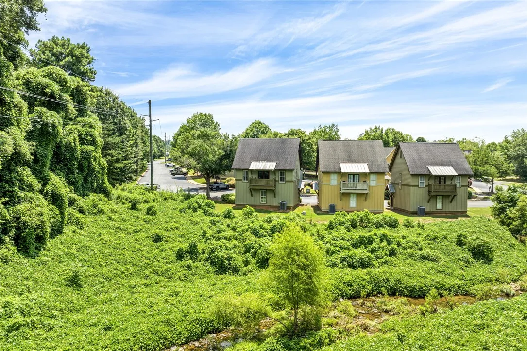 Neighboring homes feature charming balconies overlooking a verdant landscape with a winding stream.