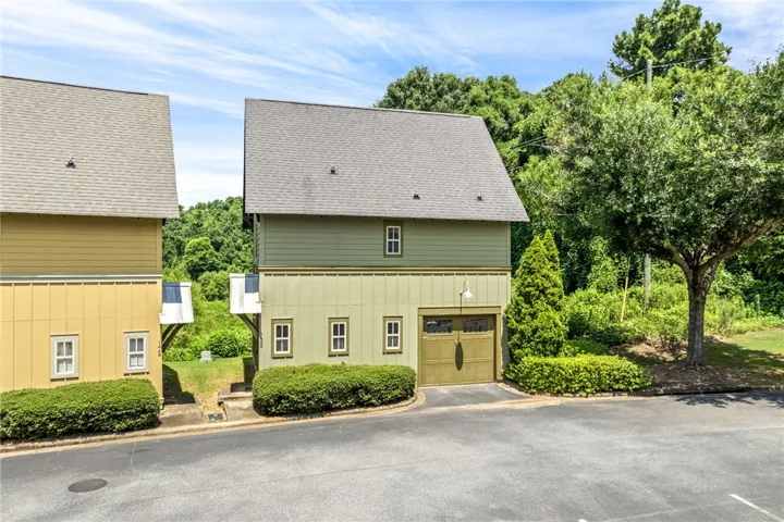 A charming green dwelling features a functional garage and neatly manicured landscaping.