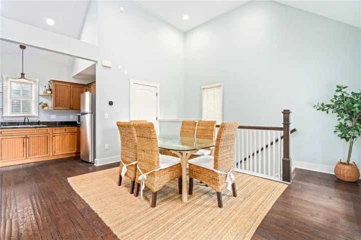 An open concept kitchen and dining area featuring high ceilings and rich wood flooring.