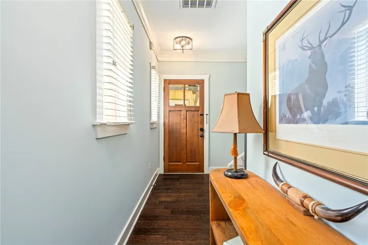 A welcoming entryway with rich wood flooring and a sturdy wooden door.