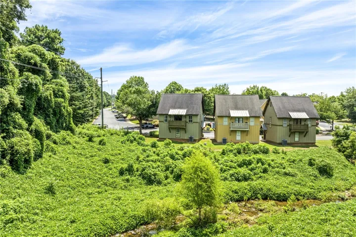 Neighboring homes feature charming balconies overlooking a verdant landscape with a winding stream.
