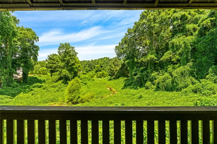 A verdant landscape unfolds from a balcony, showcasing lush greenery under an open sky.