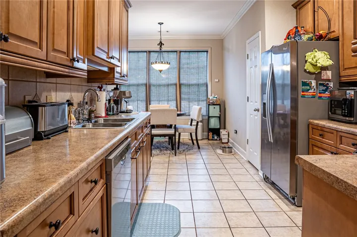 A functional kitchen with warm wood cabinetry and durable tile flooring, opening to a sun-drenched breakfast nook.