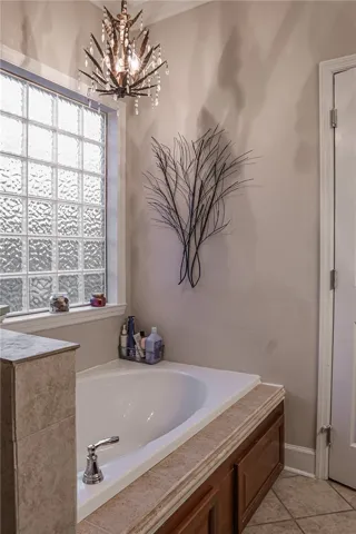 Indulge in a tranquil bathing experience with this deep soaking tub, illuminated by an elegant light fixture and privacy glass.