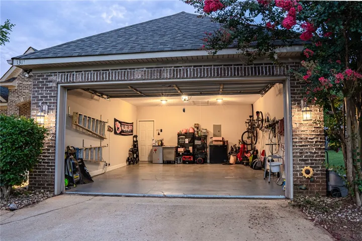 A spacious, well-lit garage offers ample storage and direct home access, framed by mature landscaping.