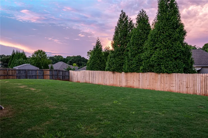 A well-maintained lawn offers ample space for outdoor enjoyment, enclosed by privacy fencing and mature trees.