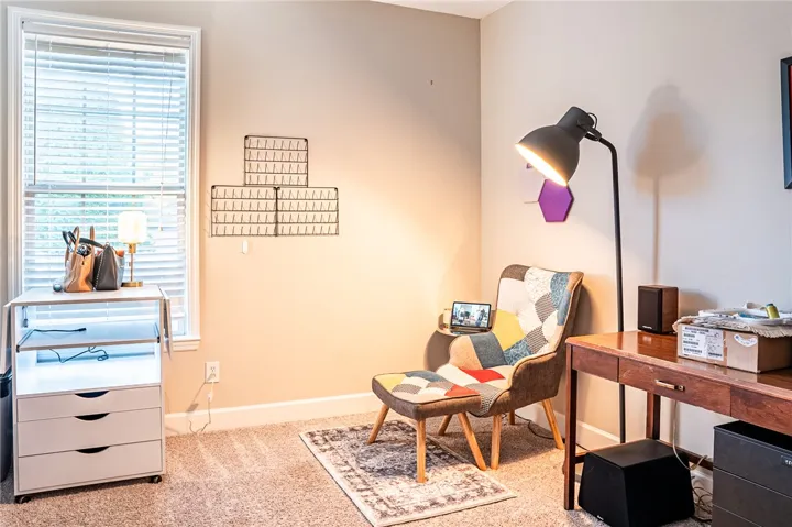 A dedicated home office space features a warm carpeted floor and ample natural light from the window.
