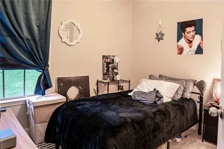 A well-lit bedroom provides ample natural light through a large window, offering a view of the outside.