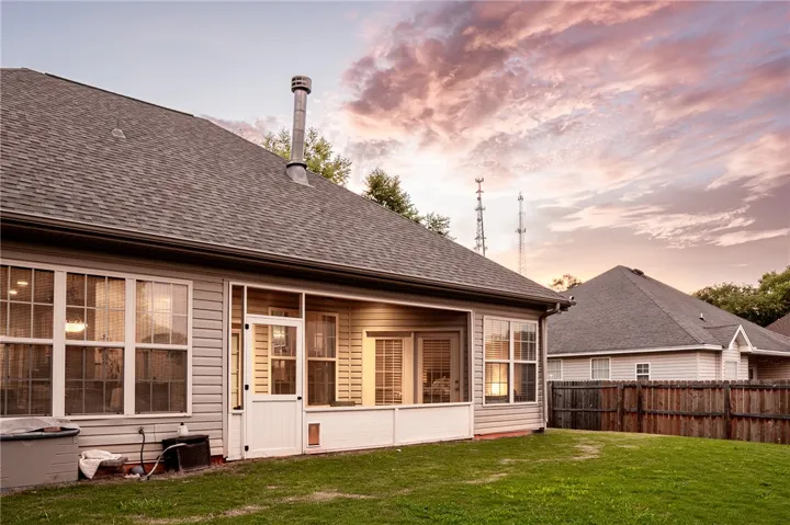 A well-maintained backyard with a screened-in porch offers tranquil outdoor living under a soft, twilight sky.