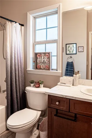 A well-lit bathroom with a bright window illuminates the vanity and shower area.