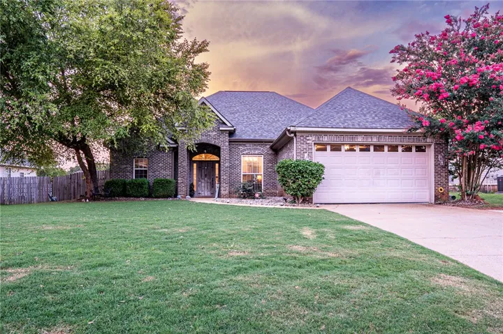 A welcoming brick facade with an arched entry and vibrant landscaping creates inviting curb appeal.