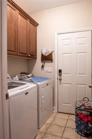 Functional laundry space featuring convenient upper cabinetry and durable tile flooring.
