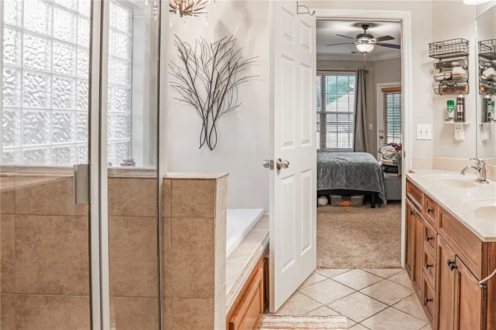 Indulge in this well-appointed primary bathroom, offering a spacious tub alongside a separate shower with a distinctive glass block window.