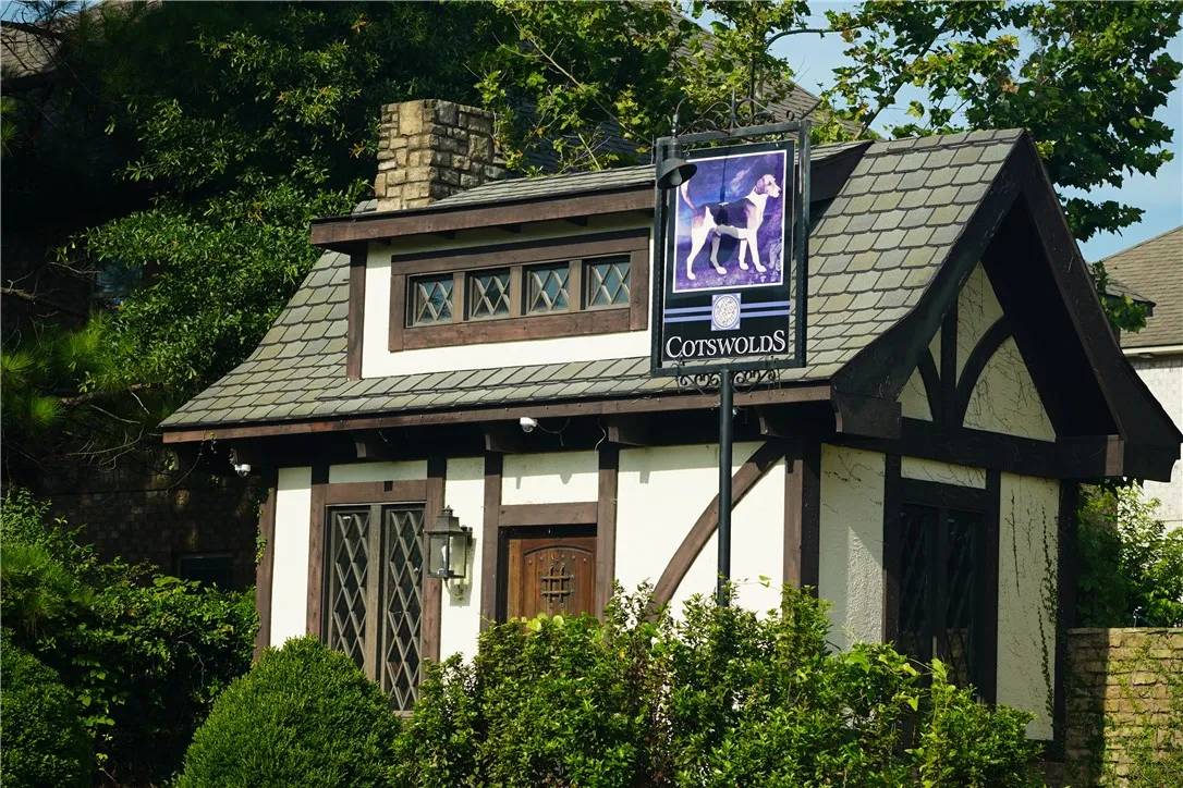 A storybook exterior boasts intricate Tudor-style architecture with diamond-paned windows and a prominent stone chimney.
