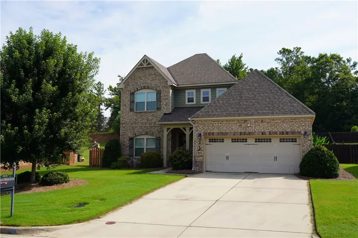 A classic brick and siding home features a welcoming front porch and an attached garage.