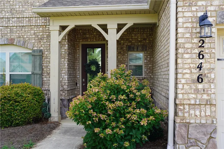 A welcoming brick facade with a charming covered entry and neatly maintained landscaping.