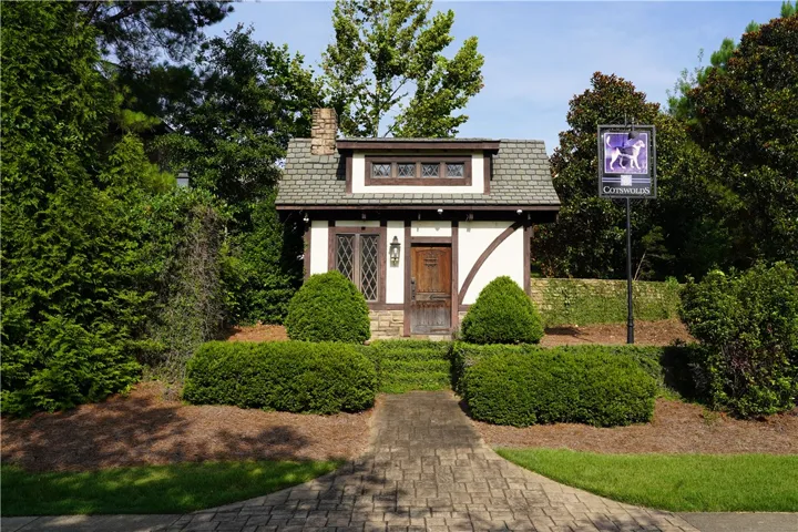 A charming Tudor-style facade welcomes visitors with a brick pathway and manicured hedges.