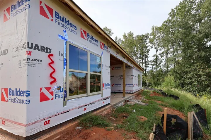 New construction underway showcases a covered porch area nestled against a lush wooded backdrop.