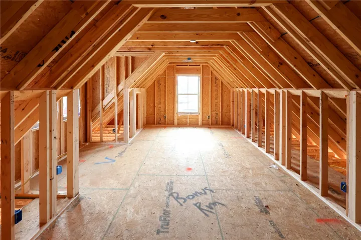 Exposed wood framing reveals the expansive potential of an unfinished upper-level bonus room.