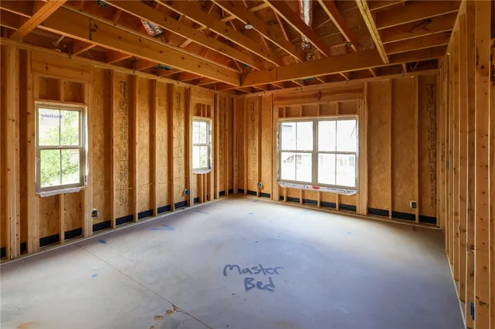 Exposed framing and subfloors highlight the early construction phase of this primary bedroom.