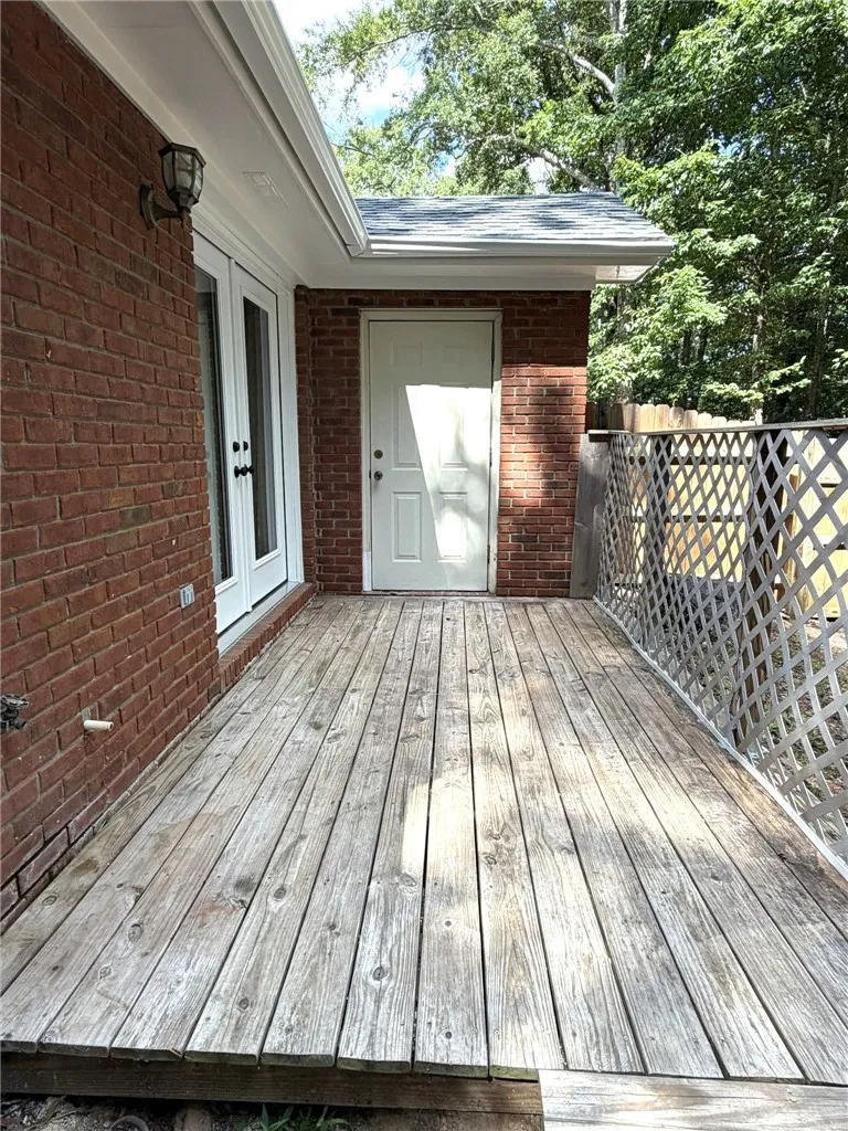 A spacious wooden deck provides an inviting outdoor extension to the brick-faced home.