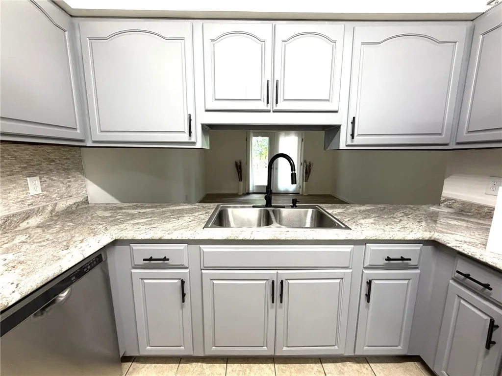 A well-appointed kitchen features ample cabinetry, stone counters, and a double basin sink.