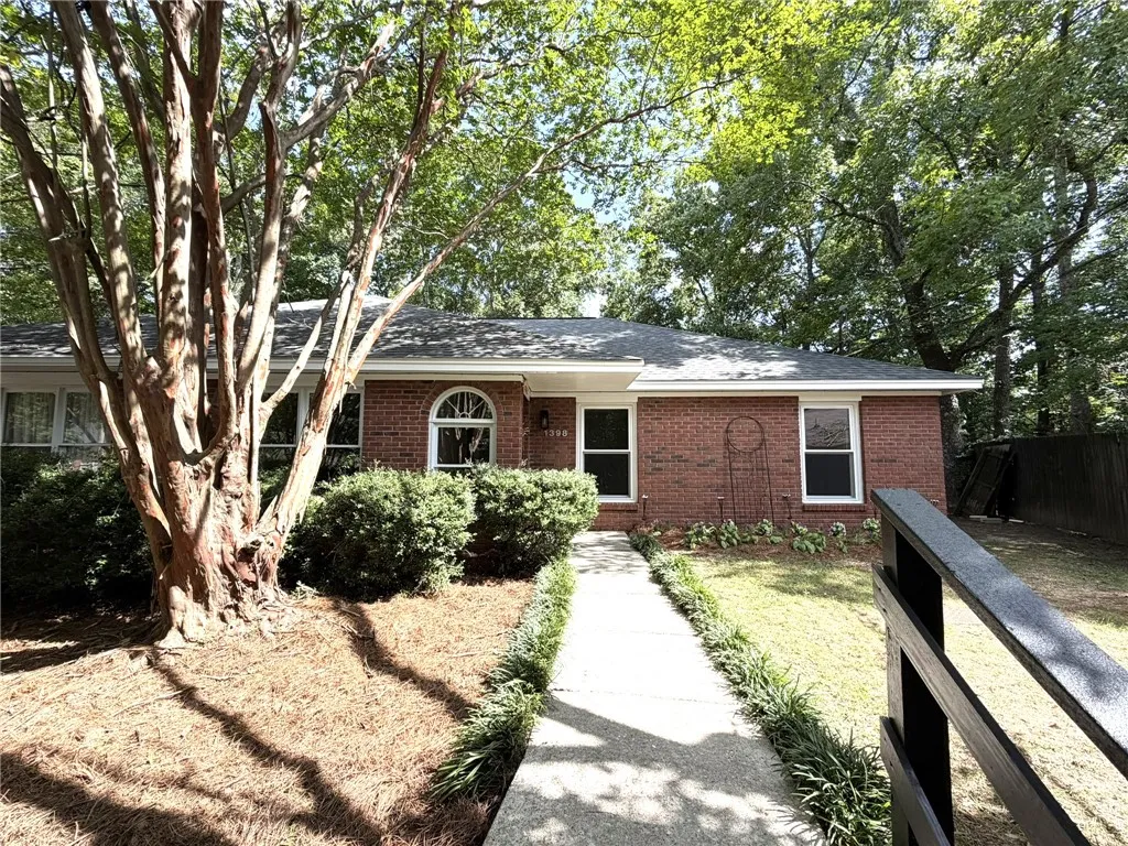 A classic brick exterior welcomes with mature trees and a manicured walkway.
