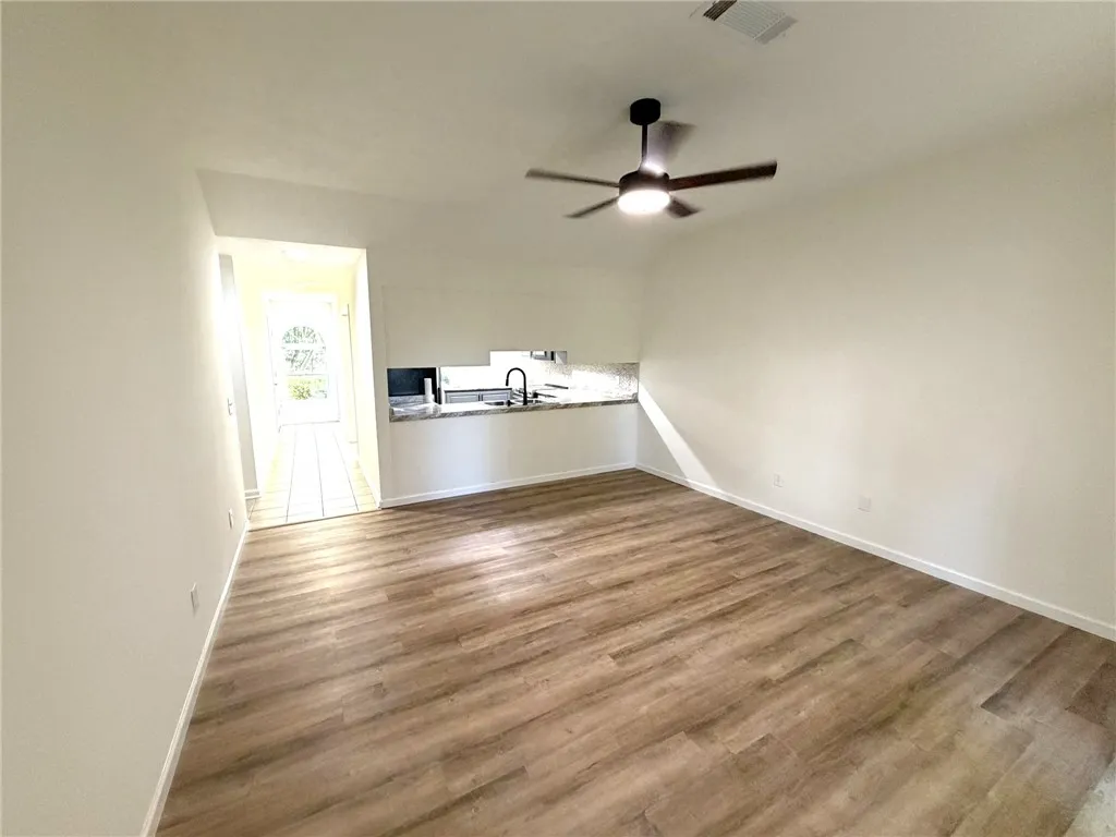Laminate flooring extends through this welcoming space, anchored by a modern ceiling fan.